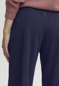 Navyblauwe joggingbroek met een zachte textuur en een subtiel gemêleerd patroon. Voorzien van een verborgen rits en een ontspannen pasvorm.