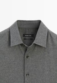 Maglia grigia a maglia con colletto, caratterizzata da un motivo testurizzato, tre bottoni neri e un'etichetta con la scritta "Massimo Dutti" all'interno del collo.
