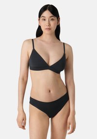 Černý bikiny set obsahující trojúhelníkový bralet s tenkými ramínky a odpovídajícími nízkými kalhotkami, vyrobený z hladkého materiálu s minimem švů.