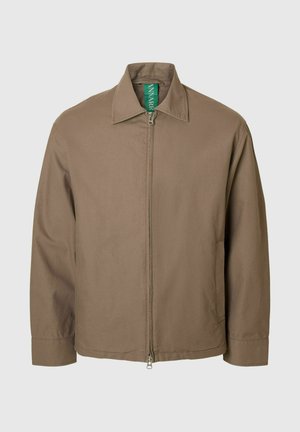 Giacca marrone con cerniera, colletto a punta, maniche lunghe e una texture liscia; presenta un'etichetta verde visibile al collo.