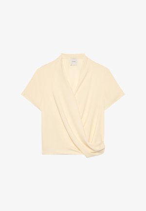 Μπλούζα σε κρεμ απόχρωση με κοντά μανίκια, μπροστινή σχεδίαση τύπου wrap και διακριτική πινελιά ντραπέ, με V-λαιμόκοψη και ελαφρύ ύφασμα.