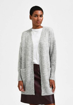 Light gray knitted cardigan with open front, long sleeves, and two front pockets. Soft texture, falls below hips, worn over a white top.