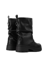 Botas de cuero negras hasta el tobillo con diseño arrugado, suelas de goma y detalles metálicos en las lengüetas. Acabado texturizado y tacón grueso.
