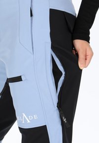 Blue and black insulated pants with zippered pockets and smooth texture, featuring logo detail and contrasting panels for added functionality.