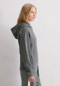 Szary sweatshirt z kapturem, z długimi rękawami i luźnym krojem. Wykonany z miękkiego materiału, z ściągaczami przy mankietach i u dołu.