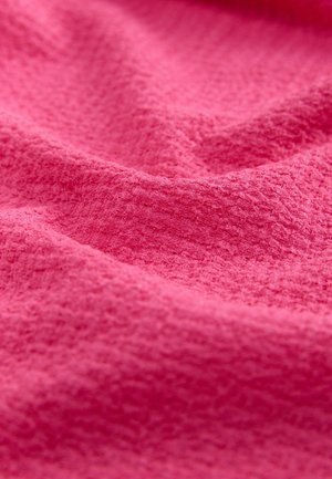 Kirkkaan vaaleanpunainen kangas, jossa on teksturoitu pinta. Se esittelee pehmeitä, aaltoilevia taitoksia, jotka luovat syvyyttä ja visuaalista kiinnostavuutta.
