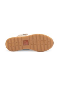 Zapato de ante beige con una suela de goma texturizada que presenta un patrón de bloques rectangulares y un logo rojo en la parte inferior.