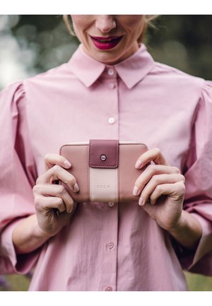Pink leather wallet with a darker pink flap, featuring a white stripe and embossed "VUCH" logo. Zipper closure, sleek design.