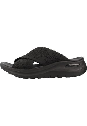 Sandalia negra tipo slip-on con correas de punto texturizadas y una suela gruesa acolchada diseñada para la comodidad y soporte.
