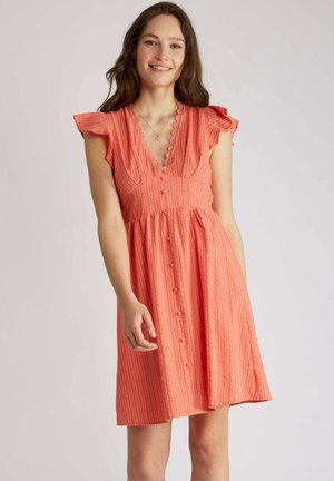 Robe corail longueur genoux avec manches courtes évasées, décolleté en V, fermeture à boutons sur le devant, et tissu texturé avec de subtiles rayures verticales.