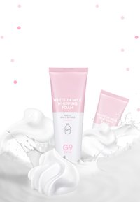Blanc dans de la mousse de lait fouettée par G9 SKIN dans un tube rose, avec du texte blanc. Entouré d'une mousse semblable à du lait et de textures douces et tourbillonnantes.