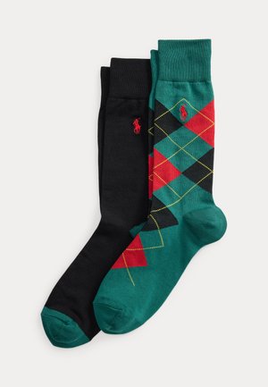 Une paire de chaussettes noires avec des orteils verts et une paire de chaussettes vertes avec un motif losanges rouge et noir, toutes deux avec une broderie de logo rouge.