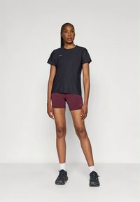 Svart treningst-skjorte med korte ermer og rund hals, kombinert med burgunder shorts. Brukes med svarte sko og hvite ankelsokker.