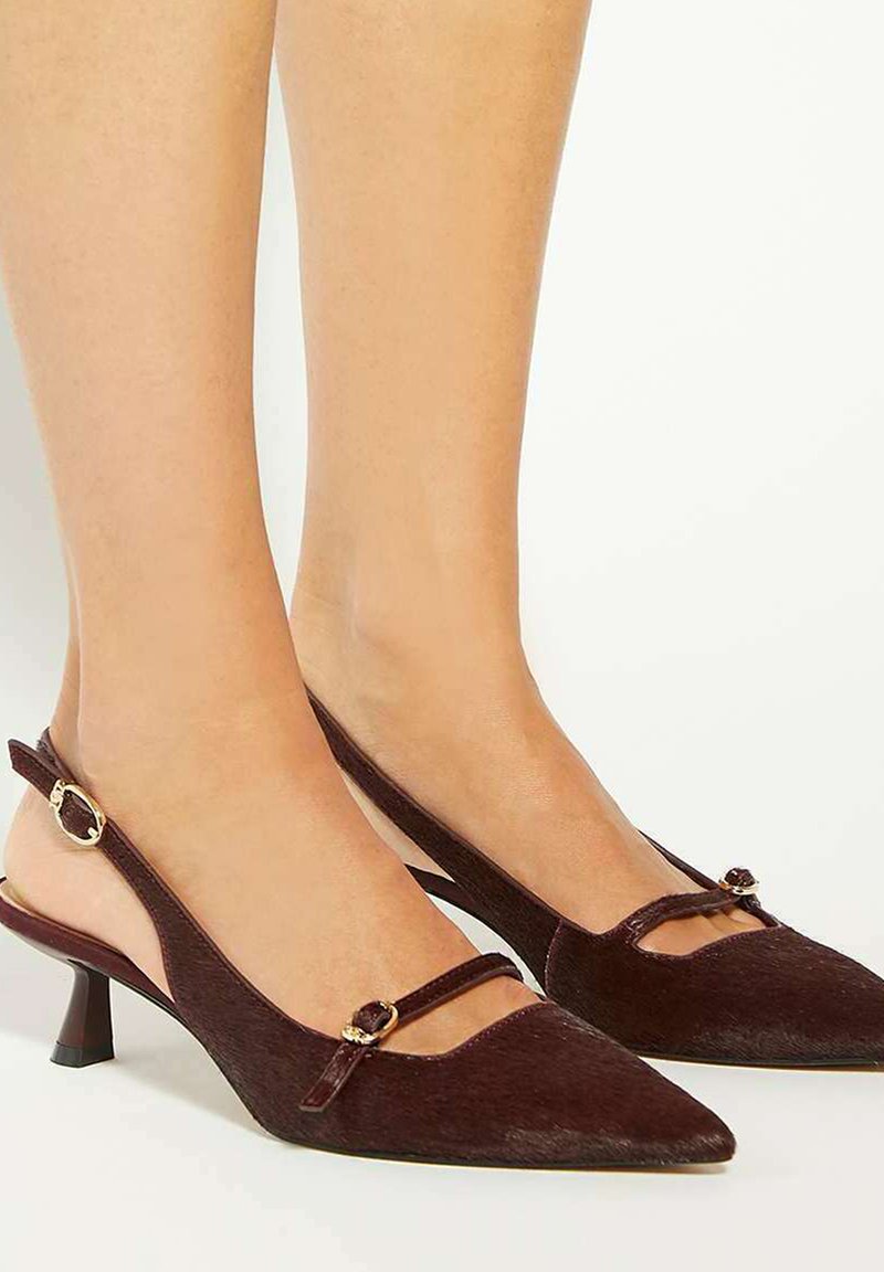 Brown suede slingback heels with a pointed toe, featuring a cutout design and small heel, adorned with a gold-tone accent detail.