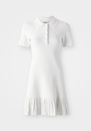 White knitted polo dress with short sleeves, button detail at collar, and a textured flounce hem. Features logo embroidery on chest.