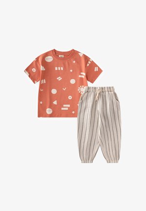 Conjunto infantil con una camiseta de manga corta naranja con formas abstractas blancas, combinada con pantalones beige a rayas con cintura elástica y bolsillos.