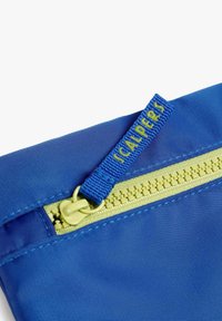 Funda de nylon azul con cremallera amarilla y tira de tirador, con una superficie texturizada y un borde cosido. La etiqueta dice "SCALPERS."