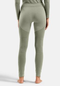 Olivengrüne, figurbetonte Leggings aus strukturiertem Stoff, mit hohem Bund und kontrastierenden, glatten Besätzen an den Oberschenkeln.