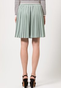 Falda plisada verde menta con cintura elástica, presenta una forma fluida y una textura suave. Terminada con un diseño de dobladillo en capas.