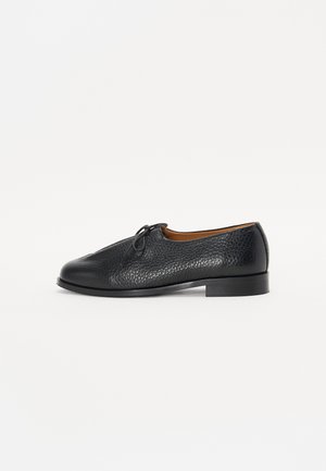 Black leather shoe with a textured finish, rounded toe, and a small bow accent on the upper. Features a low, sturdy heel.