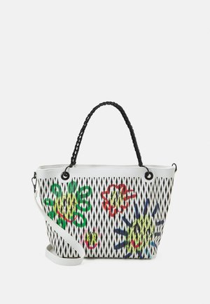 Sac fourre-tout en maille blanche avec des poignées tressées noires, présentant des motifs floraux multicolores et des œillets ronds sur le dessus pour la structure.