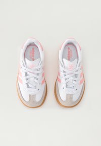 White athletic shoes with light pink stripes, gray suede accents, and white laces. Rubber sole with textured tread for grip.