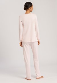 Set di pigiama rosa chiaro composto da una maglia a maniche lunghe con scollatura rifinita in pizzo e pantaloni morbidi e svasati con gamba dritta.