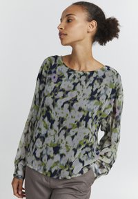 Blusa a maniche lunghe realizzata in tessuto trasparente, con un motivo astratto multicolore in tonalità di verde, blu e viola. Collo rotondo e vestibilità comoda.
