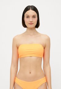 Oranžs bandeau stila bikini tops ar gludu, elastīgu audumu. Atbilstoši zema vidukļa bikini apakšgali ar sakļautām sānu detaļām. Minimālisma dizains.