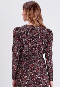 Abito a fantasia floreale con maniche lunghe, vita arricciata e spalle a sbuffo in tonalità scure con accenti rossi e beige.