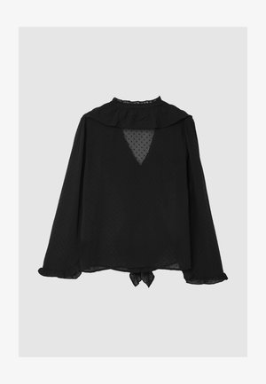 Blouse noire à manches longues avec un col à volants, texture à pois, découpe en V au dos et détail nœud à l'ourlet. Tissu transparent et coupe décontractée.