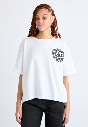 Biele oversized tričko s krátkymi rukávmi, s kruhovým čiernym grafickým textom na ľavej hrudi. Mäkko, hladké bavlnené materiály.