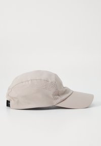 Light beige cap with a curved brim, made of smooth fabric, featuring perforated accents on the side for breathability. Adjustable back strap.