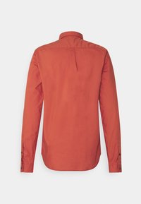 Camisa de manga larga en un vibrante color óxido, hecha de tela suave, con cuello clásico y puños con botones, con un detalle de plisado en la parte trasera.