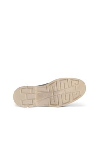 Sohle eines Schuhs, die ein strukturiertes Design mit einem tiefen Rillenmuster aufweist. Die Farbe ist ein helles Beige mit glatten Kanten und einer dezenten Markenkennzeichnung.
