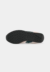 Ténis Saucony com uma sola exterior de borracha preta, entressola bege e detalhes em azul-turquesa. A superfície apresenta padrões de piso redondos para melhor aderência.