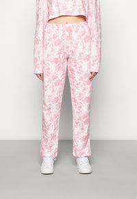 Suanças leves com efeito mármore rosa e branco, com um cós elástico, combinadas com sapatilhas brancas. Design casual e ajustado.