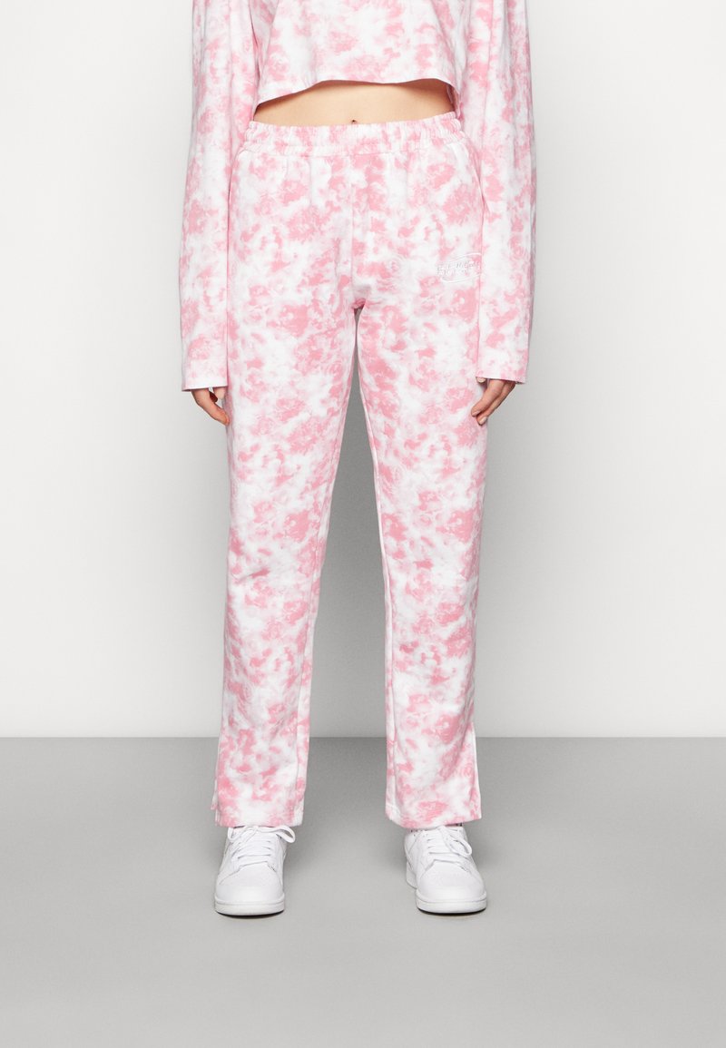 Suanças leves com efeito mármore rosa e branco, com um cós elástico, combinadas com sapatilhas brancas. Design casual e ajustado.