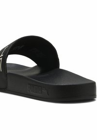 Infradito neri con suola piatta, superficie testurizzata e logo Puma in evidenza sulla cinghia. Design semplice, realizzati in materiali sintetici.