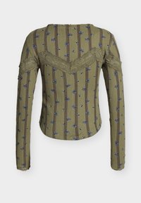 Olivově zelený žebrovaný top s dlouhým rukávem s vertikálními hnědými pruhy, malým modrým květinovým vzorem a krajkovou ozdobou na zádech a rukávech.