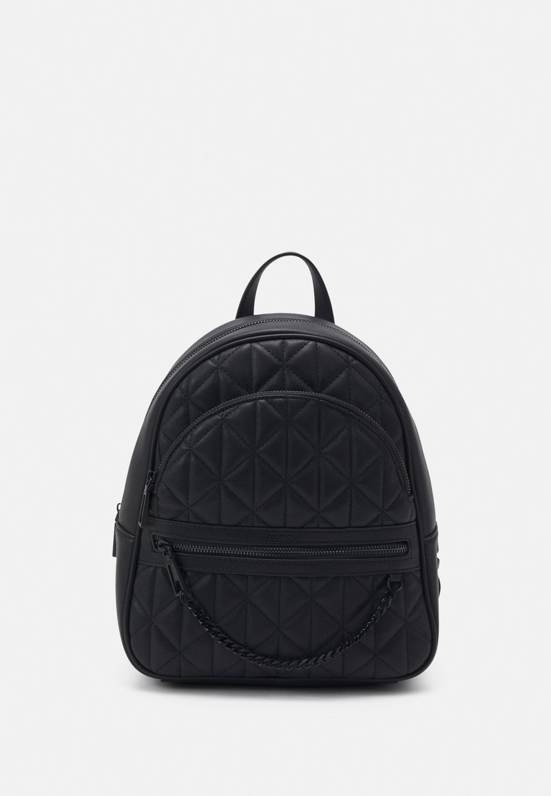 Sac à dos noir matelassé avec poches avant zippées et un détail chaîne courte, debout sur un fond blanc.