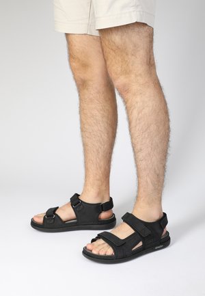 Sorte sandaler med justerbare remme, åben design, gummisål og tågreb. Har blødt materiale og metalaccenter for en sikker pasform.