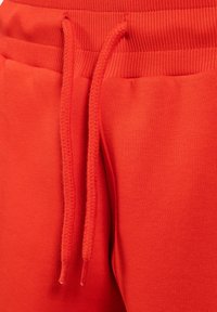 Rode sweatpants met een ribbelende tailleband, voorzien van een trekkoord van gevlochten stof. Gelijke textuur, minimalistisch design, geen zichtbare patronen.