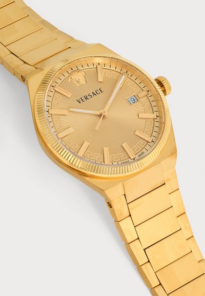 Montre-bracelet Versace en or avec un bracelet à maillons en métal, cadran rond, affichage de la date à 3 heures, logo Méduse à 12 heures et trois aiguilles indiquant 9:04:02.