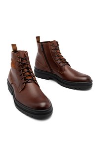 Brązowe skórzane botki za kostkę z teksturowanym wykończeniem, sznurowanym przodem, zamkiem błyskawicznym z boku i solidną czarną gumową podeszwą.