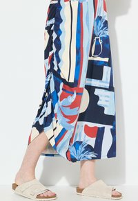Värikäs polvipituinen hame, jossa on abstrakteja kuvioita sinisen, punaisen ja kerman värissä. Valmistettu kevyestä kankaasta, joka istuu rennosti.