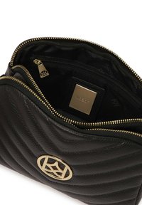 Borsa in pelle nera con design trapuntato, chiusura con cerniera e hardware dorato. L'interno presenta una fodera nera e dettagli con il logo del marchio.