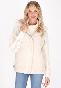 Flauschige cremefarbene Oversized-Weste mit einem Reißverschluss vorne, seitlichen Hardware-Details und einem gemütlichen Strickpullover mit strukturierten Ärmeln und hohem Kragen.