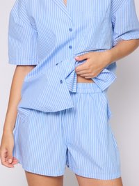 Blaue gestreifte Kurzarm-Pyjama-Set. Das Shirt hat eine Tasche und Knöpfe, während die Shorts einen elastischen Bund haben. Weicher Stoff.