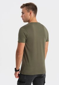 Oliven grøn kortærmet t-shirt lavet af bomuld, med rund hals og en tætsiddende design, set fra bagsiden.